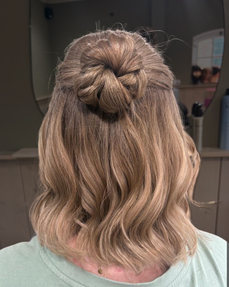 Golvend blond haar, half opgestoken in een gevlochten knot.